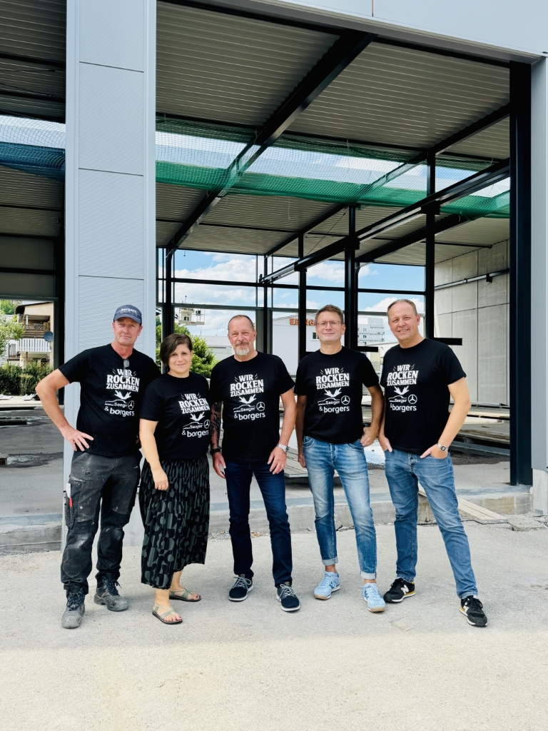 Fünf Personen mit schwarzen T-Shirts auf einer Baustelle